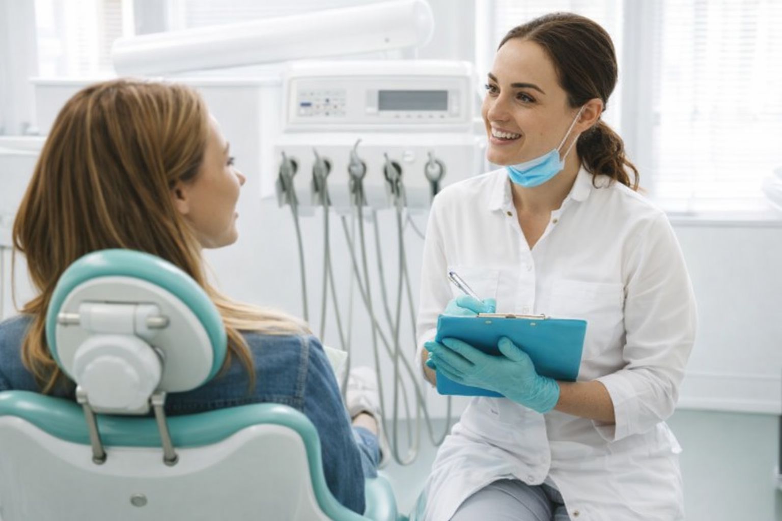 En tandläkare som pratar med en patient under en konsultation.