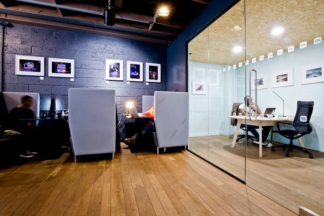 Modern coworking-miljö med enskilda arbetsbås och ett inglasat mötesrum.
